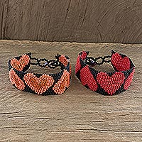 Beaded wristband friendship bracelets, 'Hearts on Black' (pair) - Pink and Red Heart Motif Beaded Friendship Bracelets (Pair)