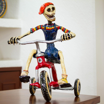 Skulptur aus recyceltem Pappmaché - Recycelte Pappmaché-Skulptur eines Skeletts auf einem Dreirad